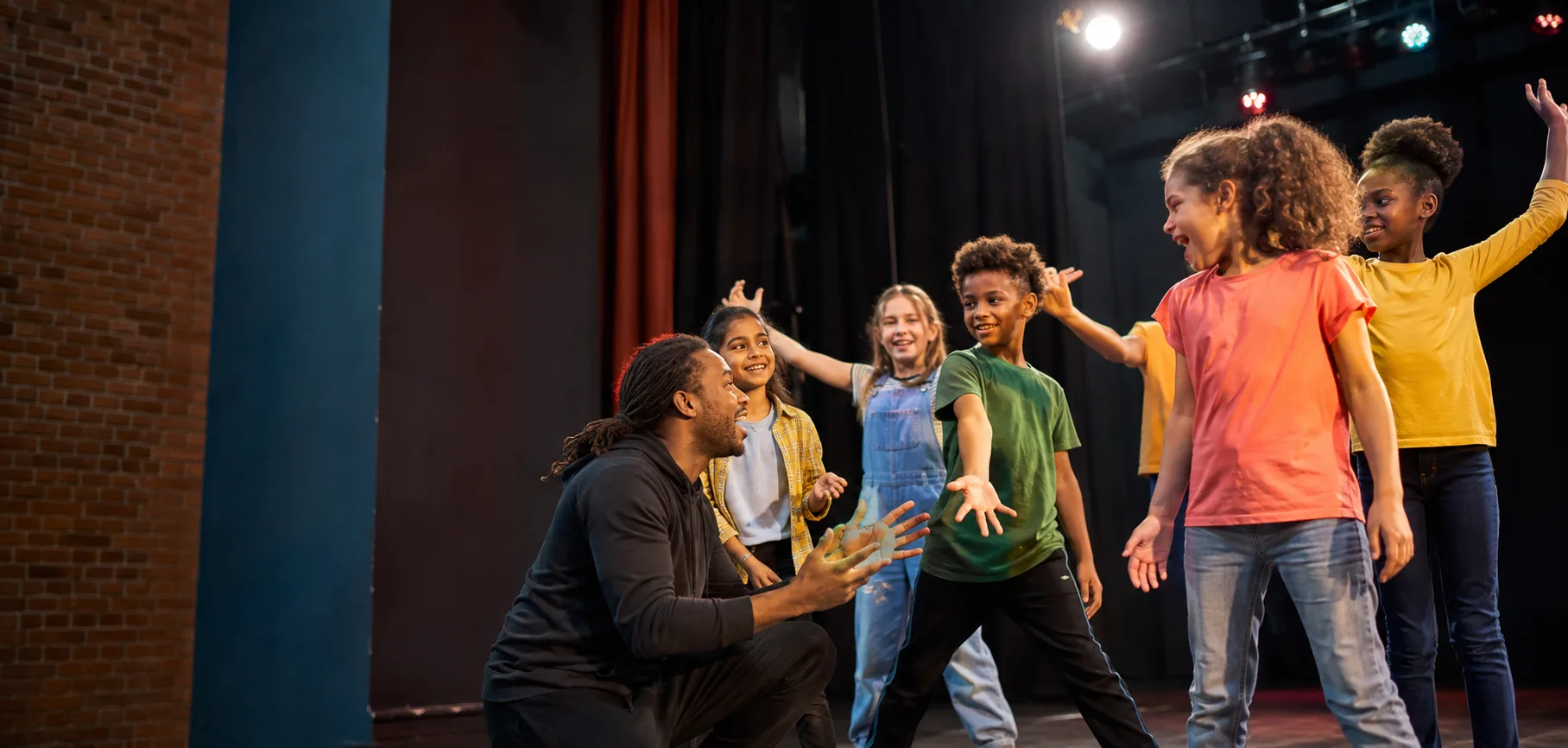 Children enjoying a theatre workshop with a supportive facilitator